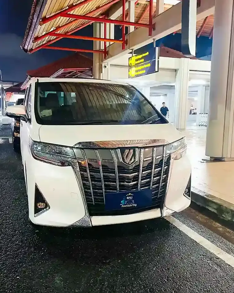 White Alphard waiting at the arrivals kerb of Ngurah Rai Airport at night
