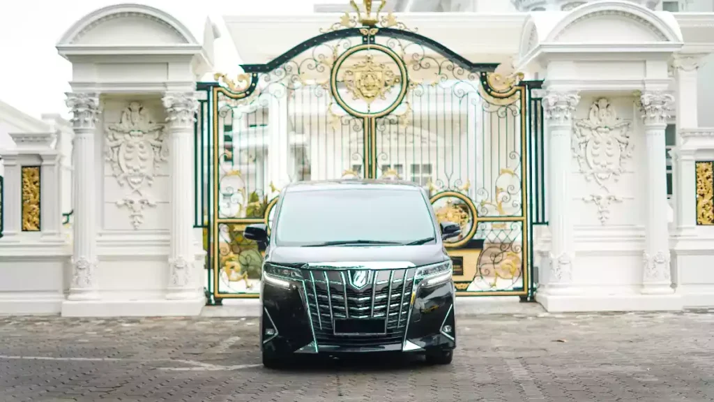 Black Toyota Alphard at a gold gate, head-on