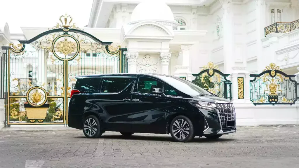 Black Toyota Alphard parked beside a white house