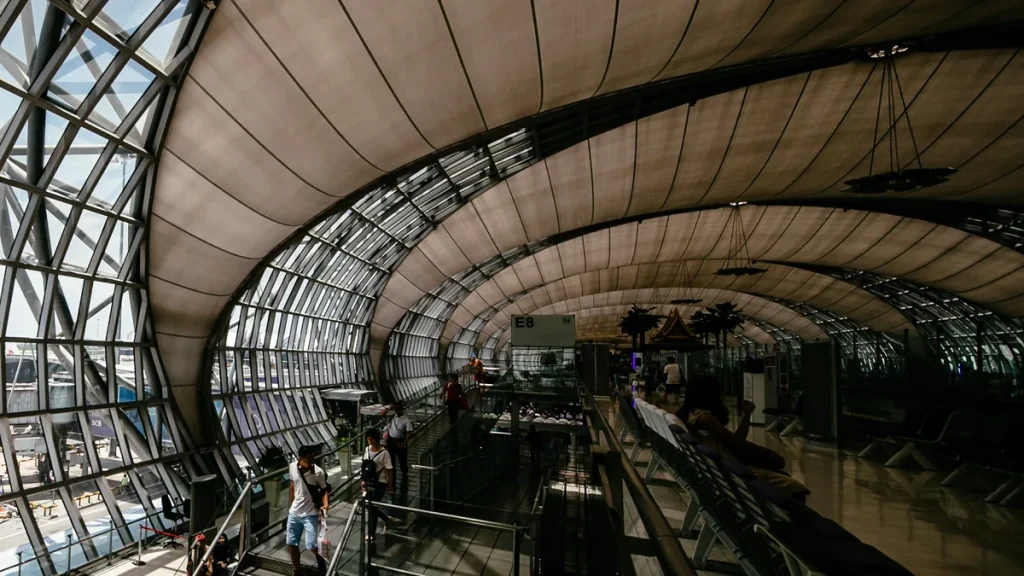 Curved airport concourse with a steel-and-glass lattice roof (Suvarnabhumi Airport, Bangkok)